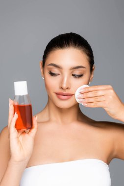 Pamuk pedi ve losyonu olan güzel bir kadın gri renkte izole edilmiş.