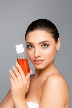 beautiful woman with bottle of lotion isolated on grey clipart