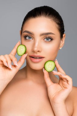 Çıplak omuzlu ve salatalıklı bir kadın gri renkte izole edilmiş.