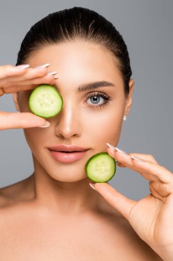 Çıplak omuzlu ve salatalıklı bir kadın gri renkte izole edilmiş.