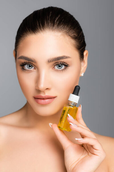 woman holding bottle with serum isolated on grey