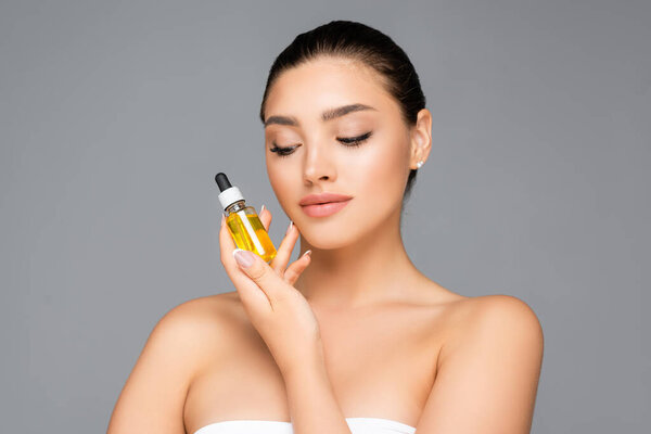 woman holding bottle with serum isolated on grey