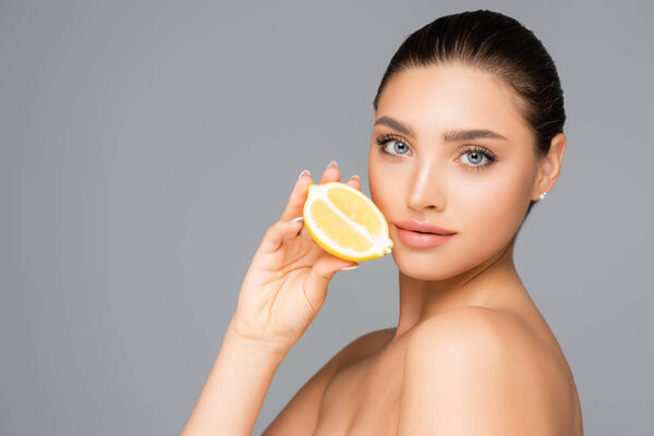 женщина с обнаженными плечами и лимоном, полуизолированными на сером