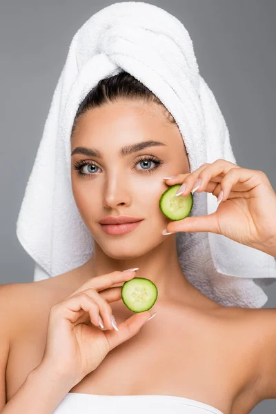 woman with towel on head and cucumber isolated on grey