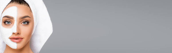 woman with towel on head and clay mask on face isolated on grey, banner