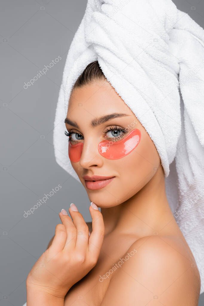 woman with towel on head and eye patches isolated on grey