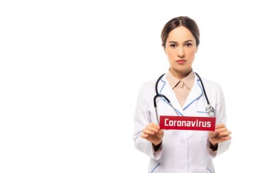Beyaz önlüklü doktor, elinde Coronavirus harfleri olan bir kart tutuyor. Beyaz harflerle izole edilmiş.