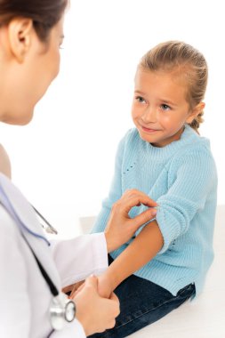 Beyaz tenli, gülümseyen çocuğun eline dokunan pediatrist seçici odağı