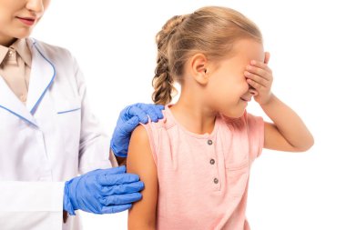 Beyaz eldivenli, çocuk doktorunun yanında gözleri kapayan korkmuş bir kız.