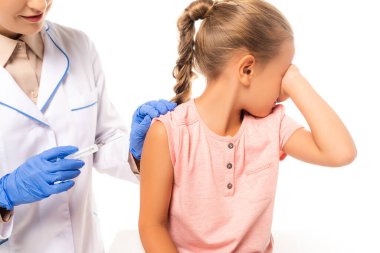 Şırıngayı elinde tutan çocuk doktoru korkmuş bir çocuğun yanında.