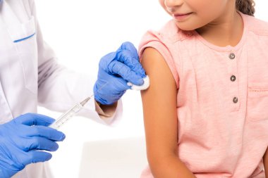 Çocuğun yanında pamuk ve şırınga tutan doktorun görüntüsü beyaza izole edilmiş.