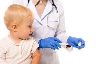 Beyaz üzerinde izole edilmiş pamuk ve şırıngayla doktora bakan bebeğin seçici odak noktası