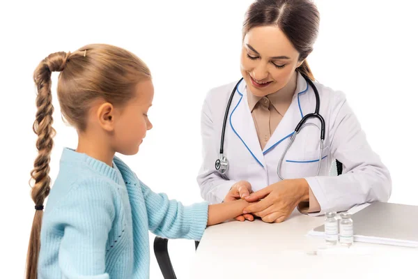 微笑的医生选择性地将焦点集中在靠近疫苗的儿童手和隔离在白色桌子上的纸夹上 — 图库照片