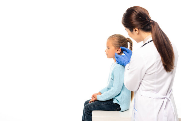 Selective focus of pediatrician in latex gloves touching ear of child isolated on white