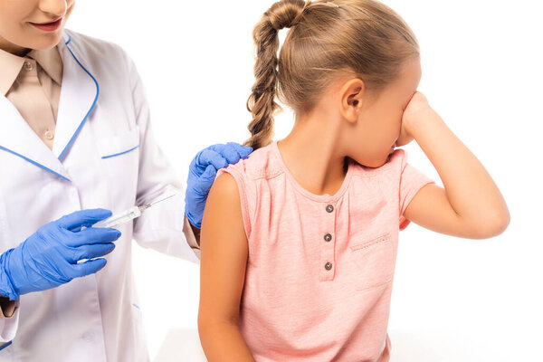 Pediatrician holding syringe near frightened child isolated on white