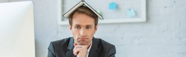 Disappointed businessman with notebook on head, leaning on hand on blurred background, banner clipart