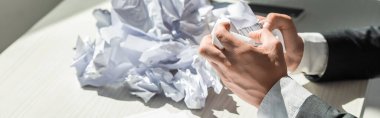 Cropped view of businessman with hands near pile of crumbled papers on blurred background, banner clipart