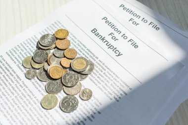 Close up view of coins on petitions for bankruptcy on white textured background clipart