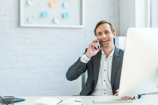 Affärsman Tittar Kameran Medan Pratar Telefon Sitter Arbetsplatsen — Stockfoto