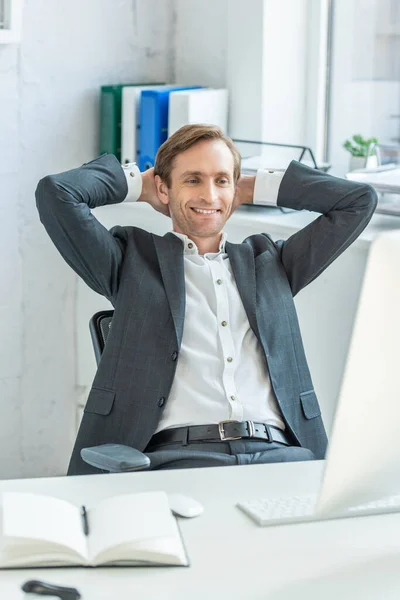快乐的生意人 手牵着头 一边看着电脑显示器 一边坐在工作场所模糊的前景 — 图库照片