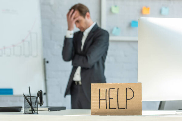 Картон с надписью на рабочем месте на фоне размытого бизнесмена