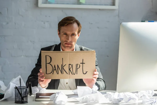 Upset Businessman Holding Cardboard Bankrupt Lettering While Sitting Workplace Crumpled — Stock Photo, Image