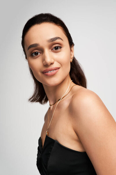 Brunette model poses confidently in a fashionable black corset and sleek backdrop.