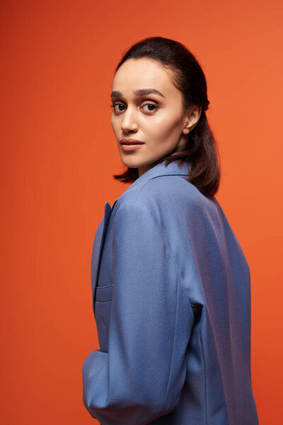 Beautiful young woman showcases her trendy outfit in a studio setting with vivid colors.