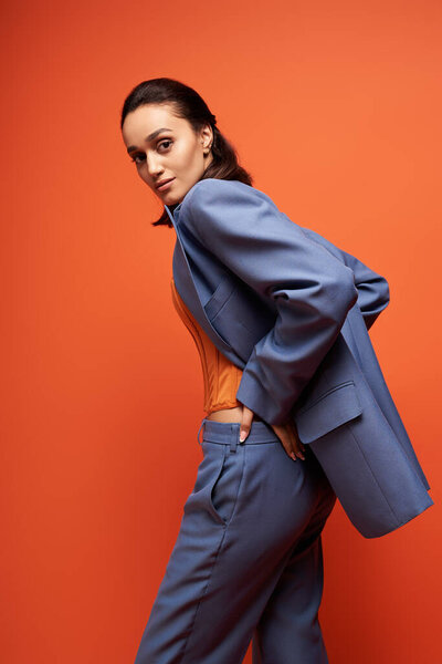 A beautiful young woman showcases her fashion sense in a blue suit paired with a corset.