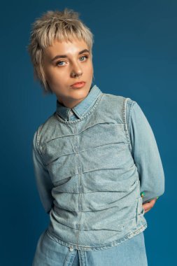 Portre, kot elbiseli, kendine güveni ve tarzı olan güzel bir genç kadını resmediyor..