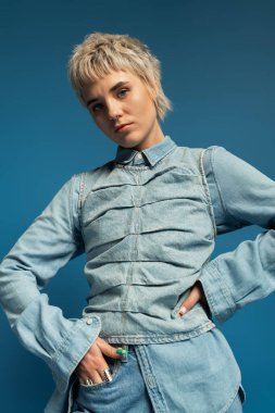 Kendine güvenen, şık kot elbiseli, kendine has stili ve güzelliğiyle hava atan genç bir kadın..