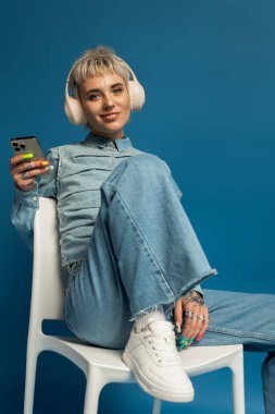 Parlak gözlü kadın kulaklıkla müzik dinlerken gülümseyerek neşe saçıyor..