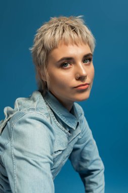 Zarif genç bir kadın zarif bir şekilde eğiliyor, şık saç stili ve moda anlayışını sergiliyor..