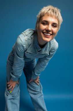 Tarz sahibi genç bir kadın şık bir kotla moda anlayışını sergileyerek ışıl ışıl gülümser..