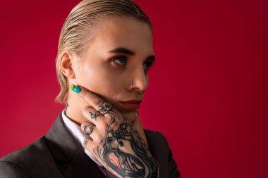 Kendine güvenen genç bir kadın düşünceli bir ifadeyle poz veriyor, eşsiz stilini ve dövmelerini sergiliyor..