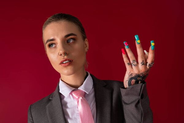 A confident woman showcases her artistic nails and stylish, bright attire.
