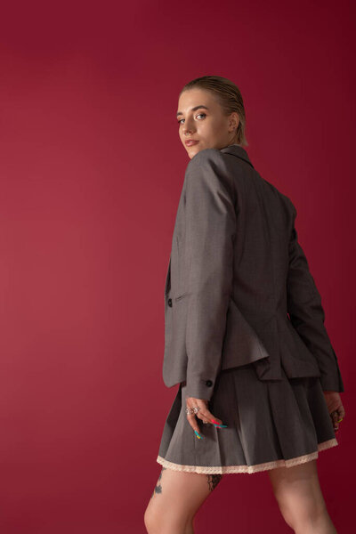 Молодая, красивая женщина демонстрирует свое чувство стиля в сером костюме и игривой юбке..