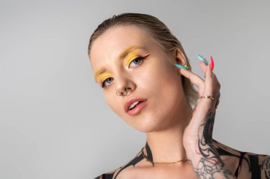 Çekici genç kadın kendine güvenen bir ifadeyle renkli makyaj ve çarpıcı özellikler sergiliyor..