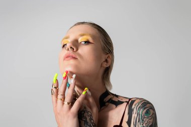 Güzel genç bir kadın zarif pozlar veriyor, cesur makyajını ve çarpıcı aksesuarlarını vurguluyor..