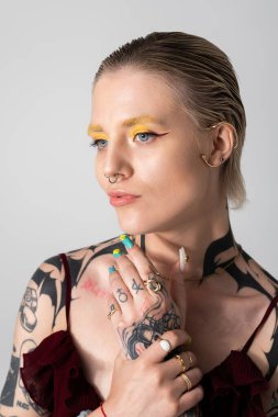 Genç bir kadın modern bir mekanda cesur dövmeleri ve eşsiz aksesuarlarıyla hayat dolu tarzını sergiliyor..