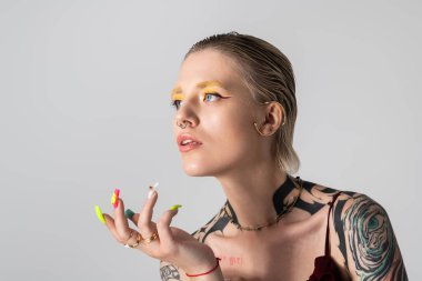 Renkli makyajlı ve dövmeli güzel genç bir kadın eşsiz stilini ve kendine güvenini sergiliyor..