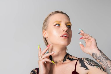 Genç bir kadın canlı tırnakları ve çarpıcı makyajıyla büyüleyici bir stil sergiliyor..