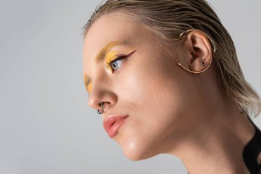 Yaratıcı bir anda yakalanan genç bir kadın canlı makyaj ve eşsiz aksesuarlar sergiliyor..