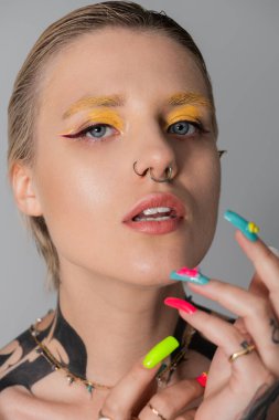Güzel bir genç kadın cesur makyajını, renkli tırnaklarını ve eşsiz tarzını sergiliyor..