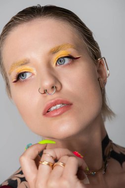 Genç bir kadın kendine özgü stilini canlı makyaj ve aksesuarlarla sergiliyor..