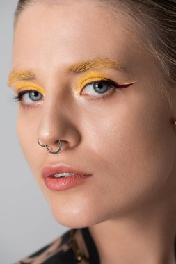 Güzel genç bir kadın cesur sarı göz makyajı ve eşsiz mücevherler sergiliyor..