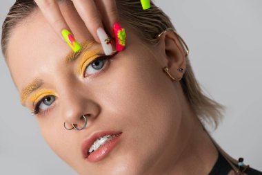 Şık bir kadın sanatsal makyajını ve canlı tırnaklarını sergiliyor..