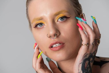 Yaratıcı makyaj ve renkli tırnaklarla eşsiz tarzını sergileyen genç bir kadın..