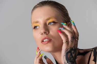 Kendine güvenen genç bir kadın şık makyaj ve şık aksesuarlarla parıldıyor. Zarif bir şekilde poz veriyor..