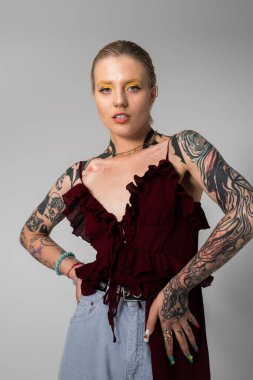 Şık bir genç kadın kendine güvenerek poz veriyor, sanatsal dövmelerini ve modasını sergiliyor..